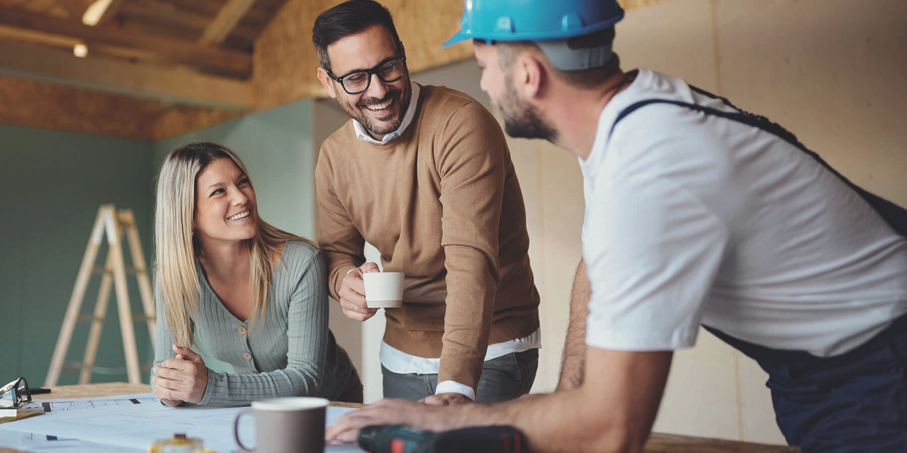 couple heureux de discuter avec un conducteur de chantier sur leur projet de construction