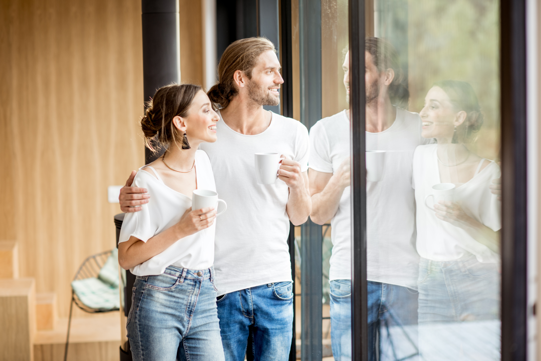 couple heureux qui regarde par la fenetre de leur nouvelle maison