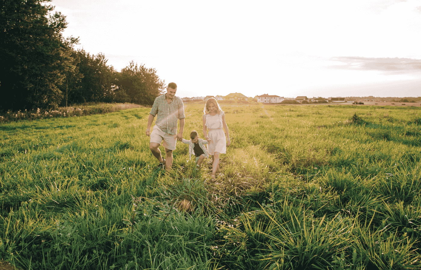 famille heureuse qui marche dans un champ avec le reflet du soleil